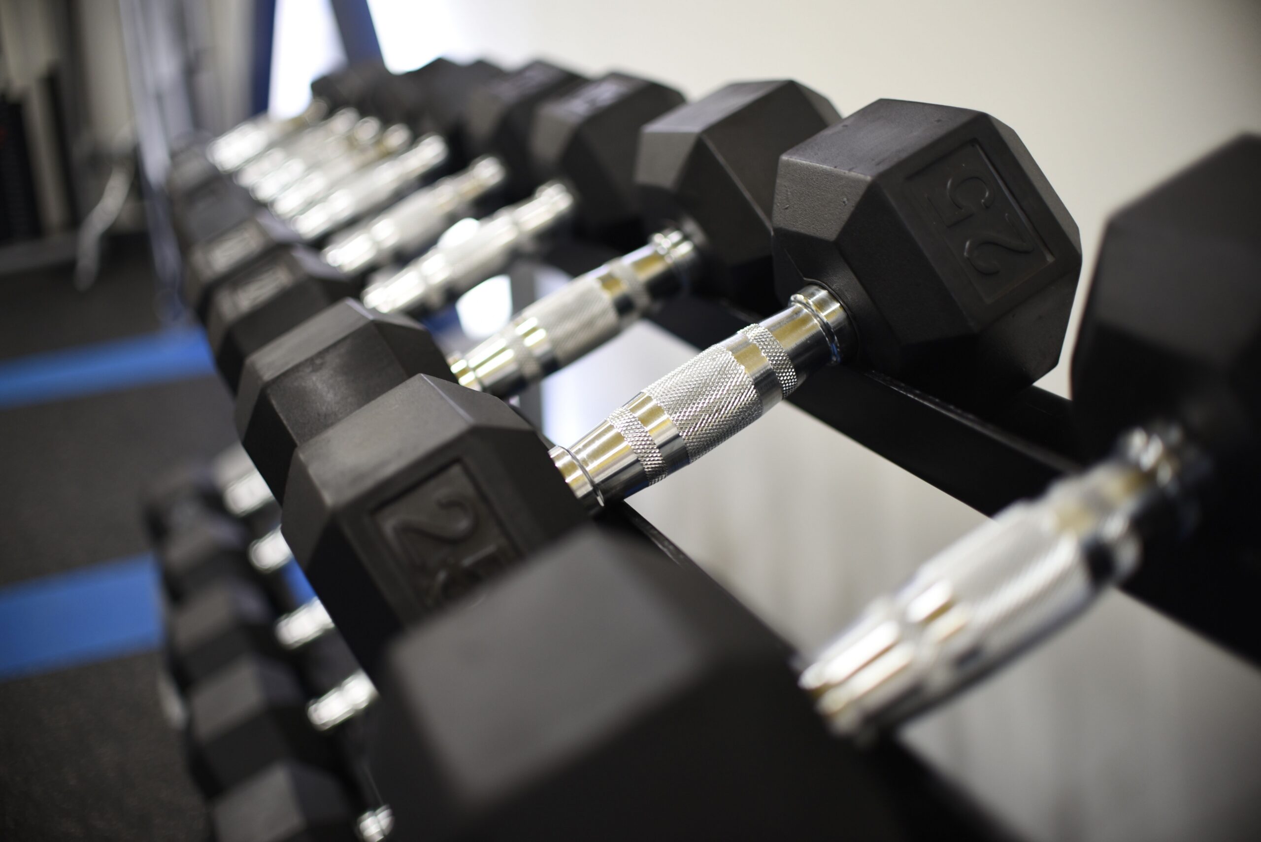 Close up of rubber coated hex dumbbells neatly arranged on a two tier weight rack scaled