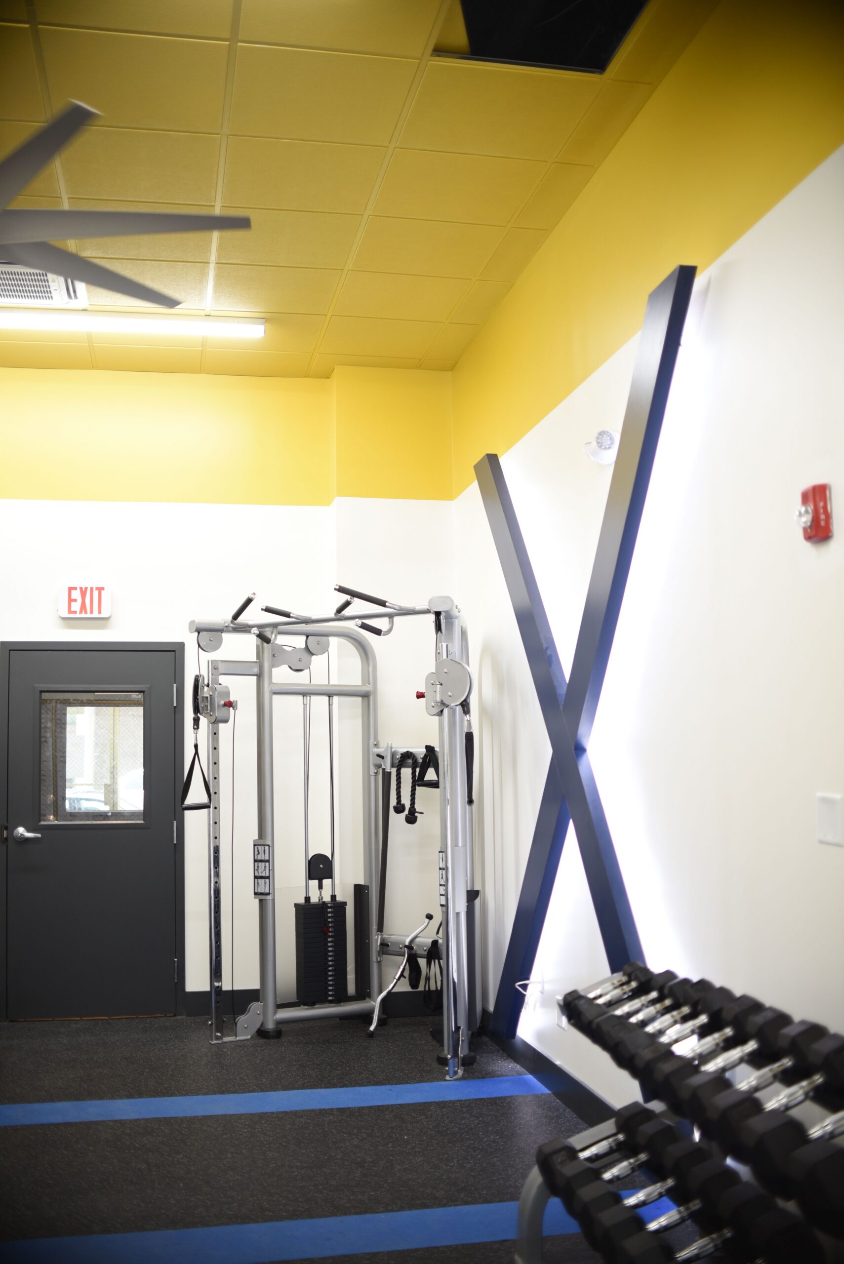 Weight training area in apartment fitness center with cable machine station and dumbbell rack scaled