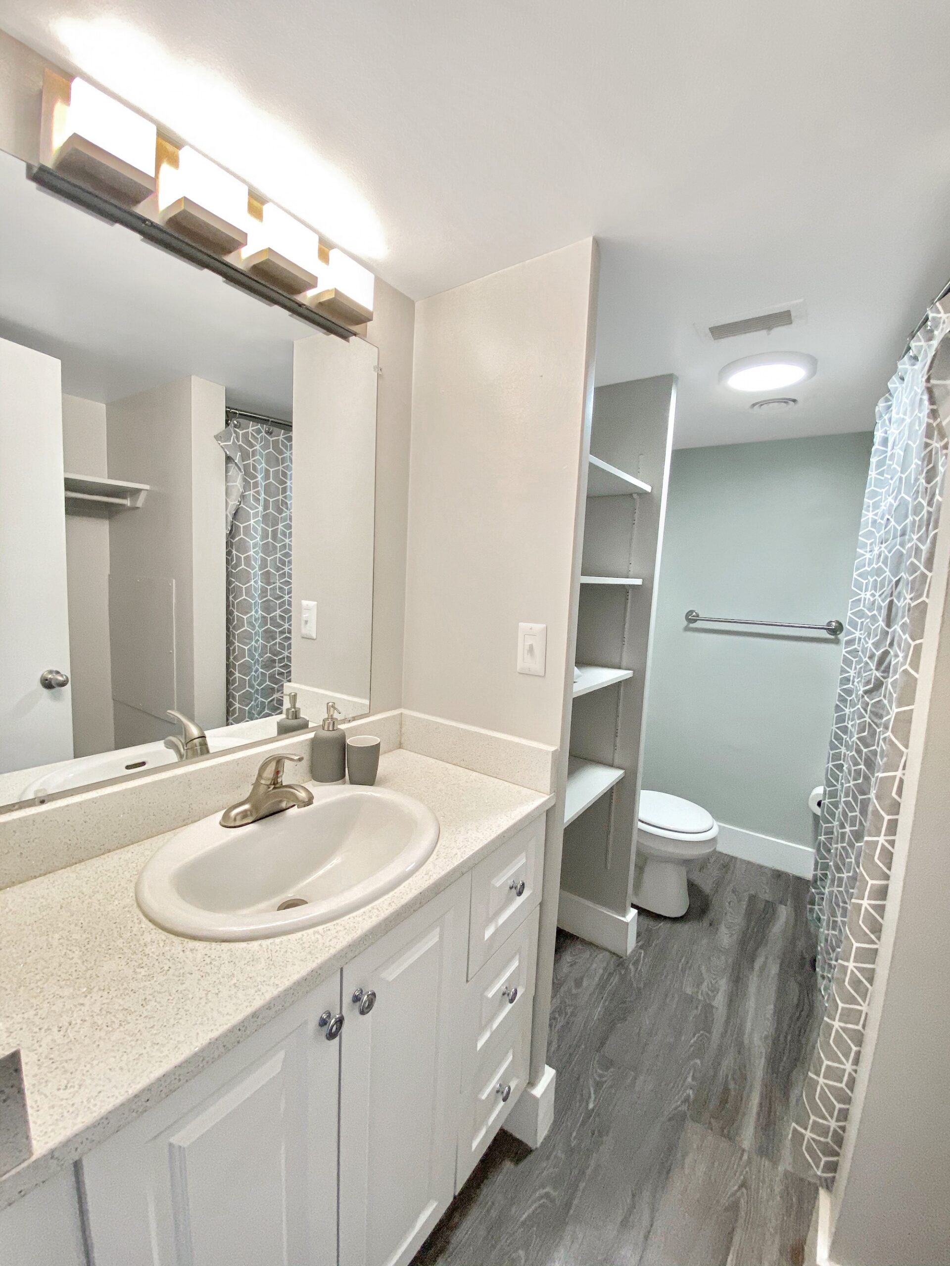 updated studio apartment bathroom white vanity granite counter scaled
